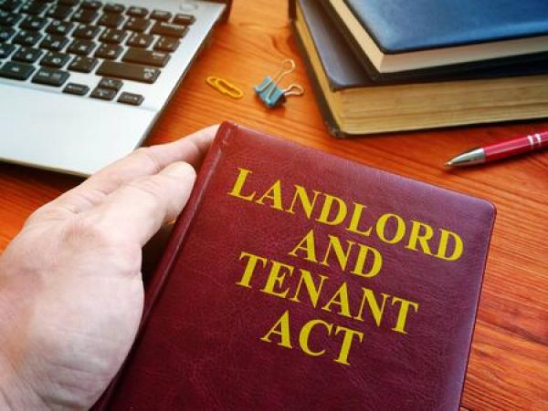 A hand holds a book that says "Landlord and Tenant Act"