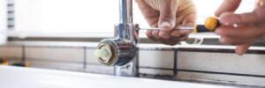 A man fixes a leaking faucet with a screwdriver.